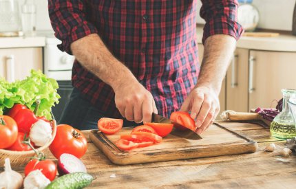 image of food preparation - man chopping tomatoes